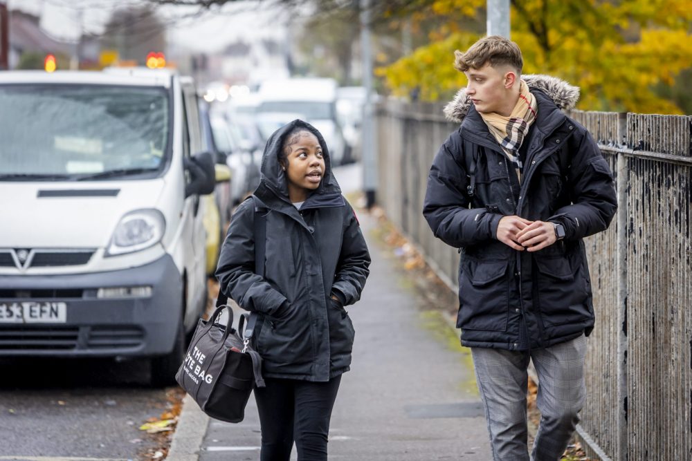 Two young people are walking down the street talking