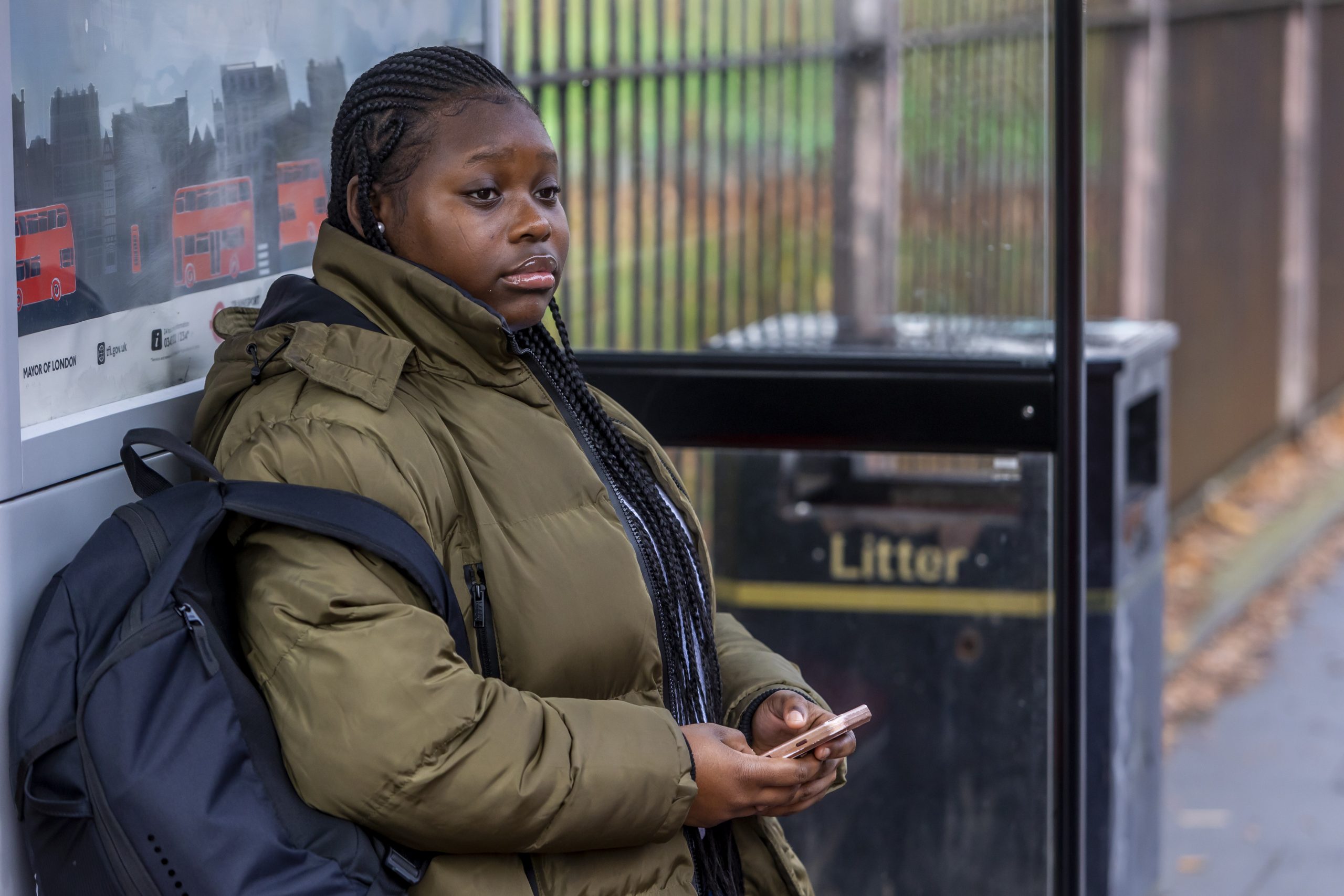 A young person is sitting at a bus stop thinking about their rights to medical treatment