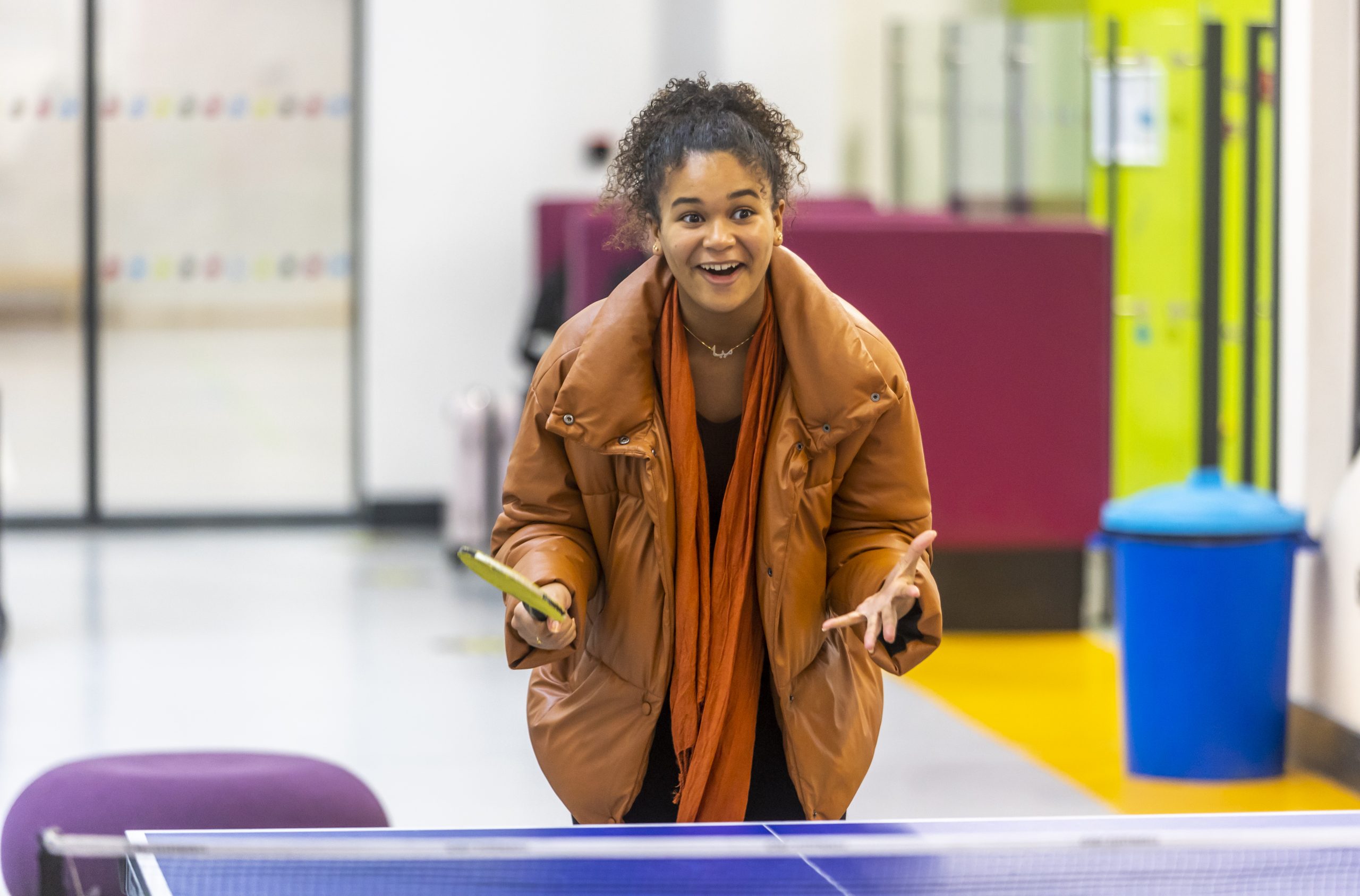 A young person is smiling as they play table tennis, describing how they blagged their way into a club for free