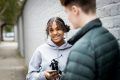 A young person is talking to a friend whilst holding their phone. They are discussing university clearing.