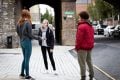 Three young people are standing in the street talking about insomnia
