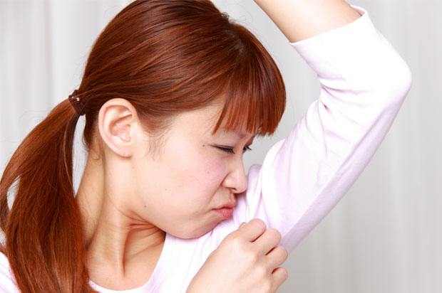 Girl smelling her own armpit and wrinkling her nose