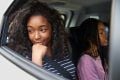 Two young women are sitting in a car. They are headed for a family holiday. This is a wide-angle image.