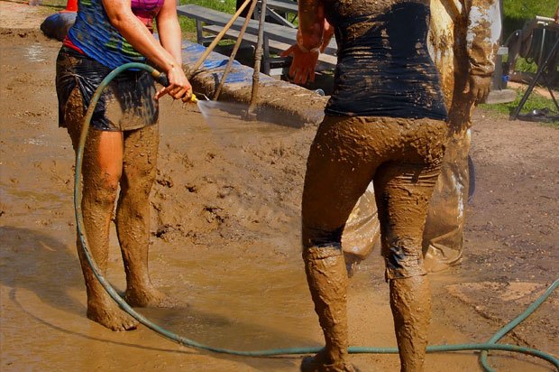 Very muddy people trying to hose off