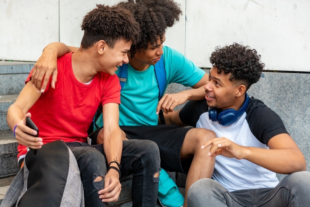 A group of young men are laughing. They are in a love triangle. This is a wide-angle image.