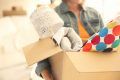 A young woman is holding a moving box. She is moving in with a new family. This is a close-up image.