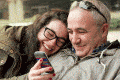 daughter and dad laugh at something on her phone