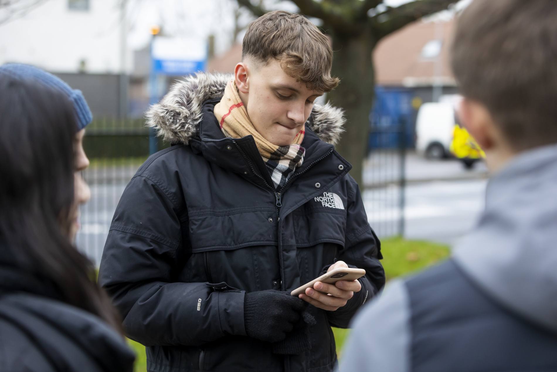 A young man is checking his phone. He is looking for part time jobs. This is a wide-angle image.