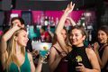 group of women dancing in a club with drinks in their hands.