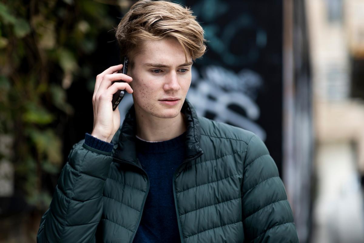 A young man is on the phone. He has just been made redundant. This is a close-up image.