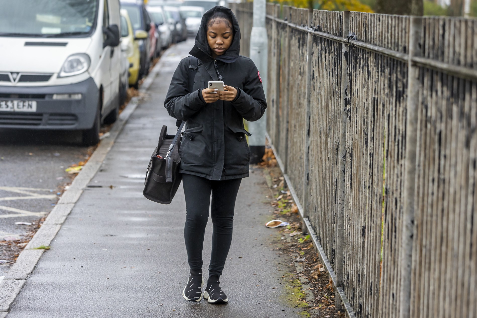 A young woman is walking back home from her second job. This is a full-body image.