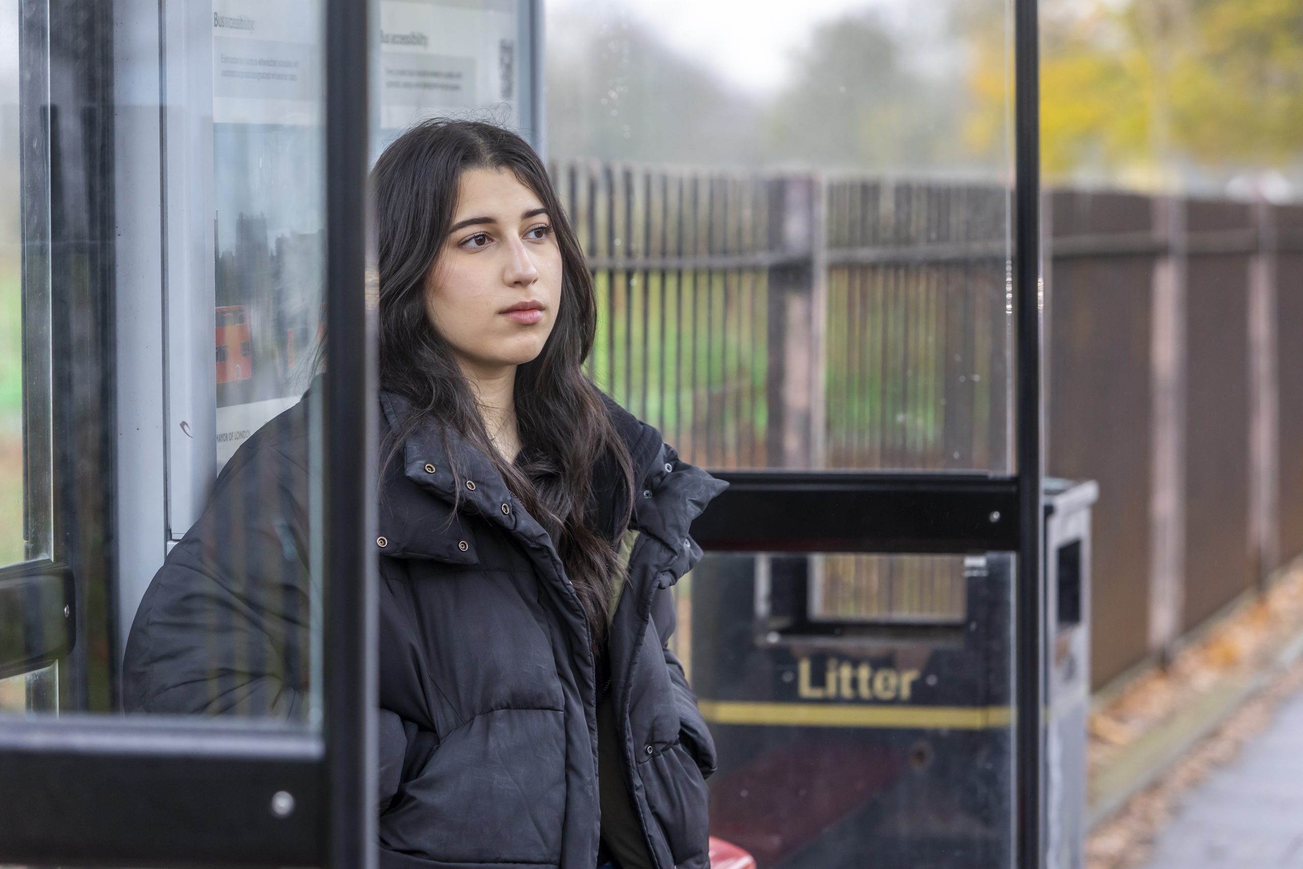 A young woman is sitting at a bus stop. She is thinking about losing her virginity.