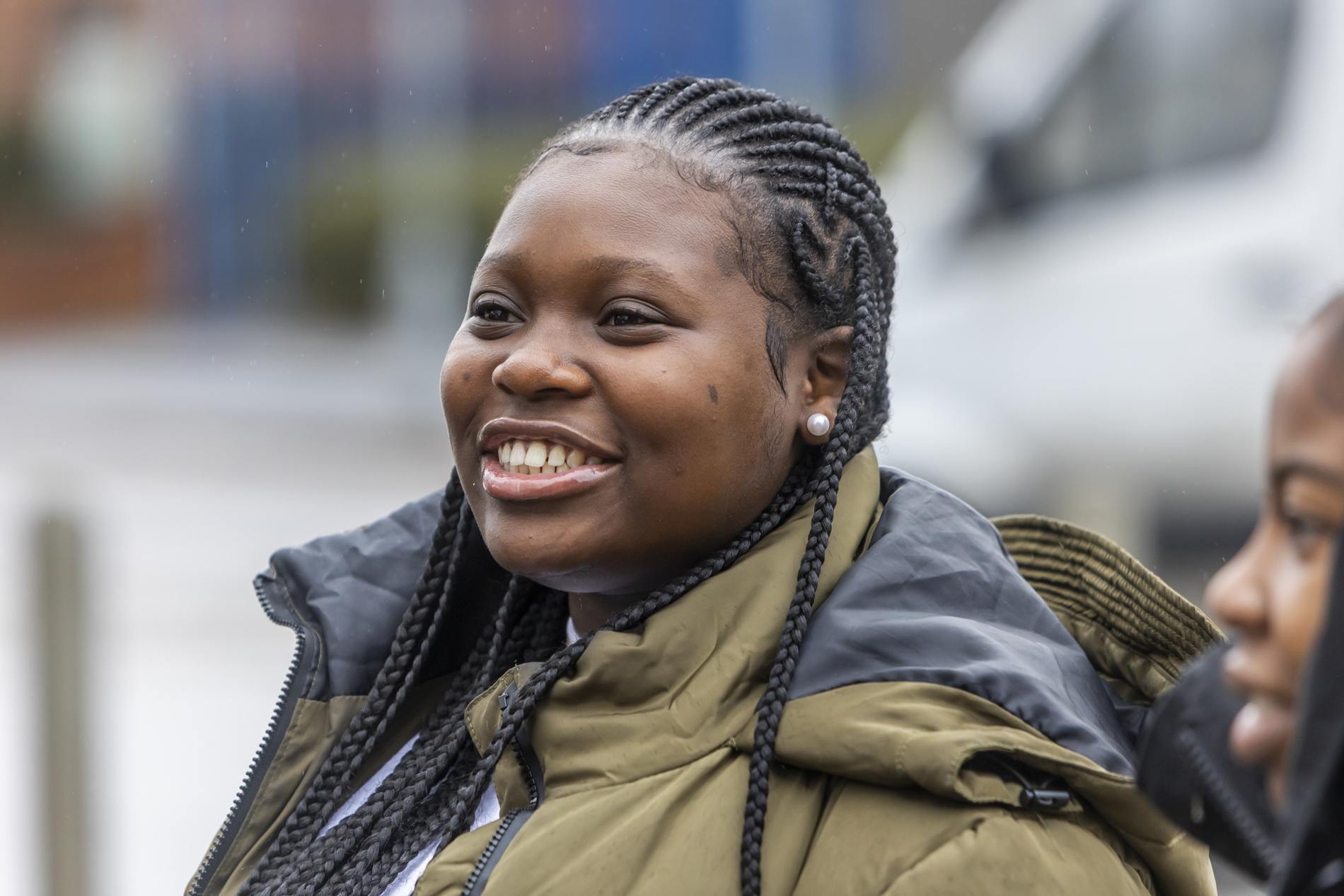 A young woman is smiling. She is thinking about volunteering at Christmas. This is close-up image.