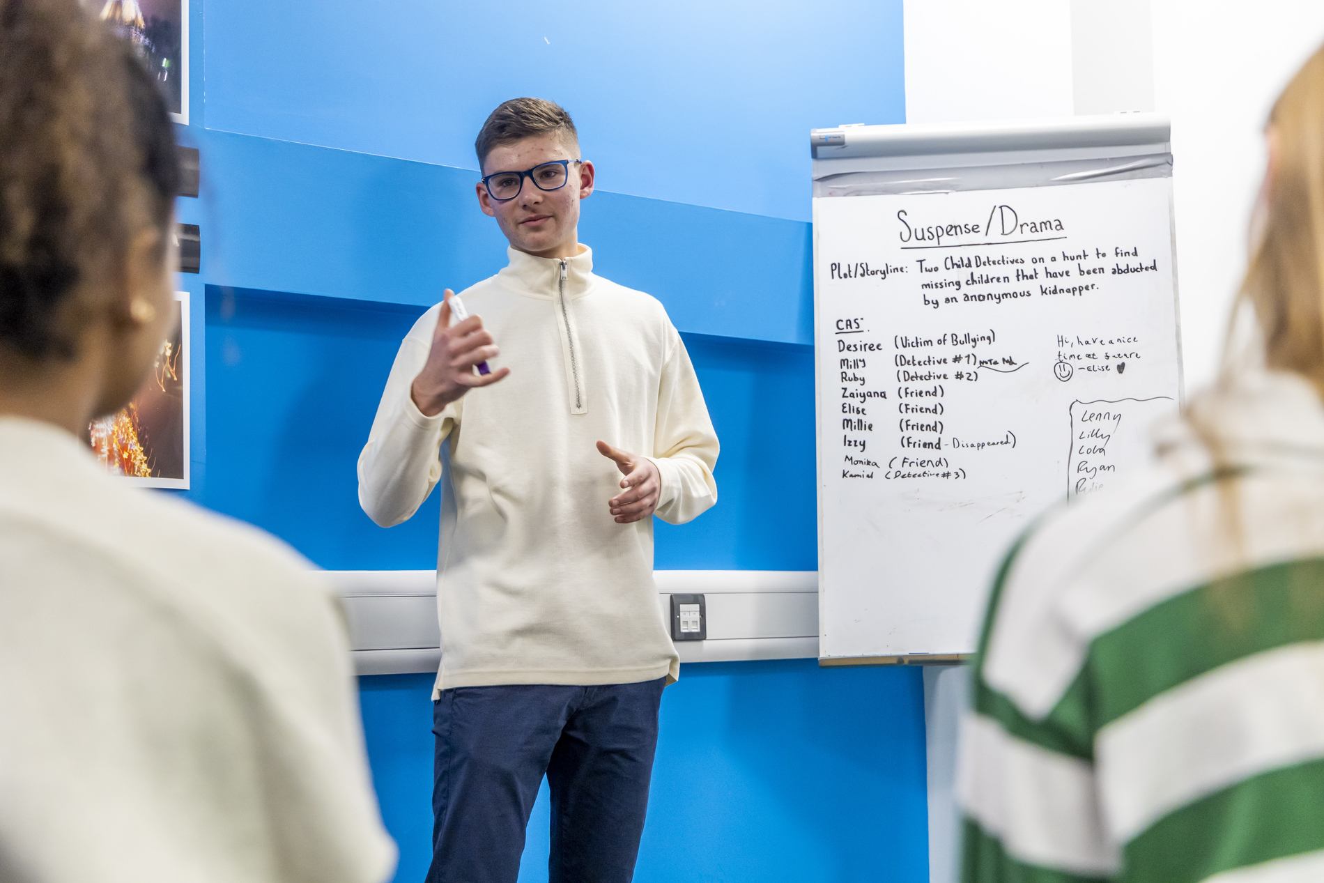 A young man is giving a presentation on how to write a CV. This is a wide-angle image.