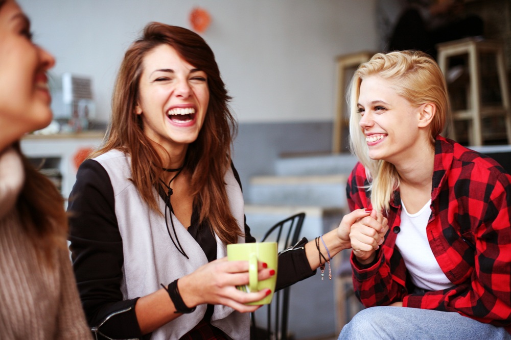 A group of young people are sitting down. One of them is jealous of her friend. This is a wide-angle image.