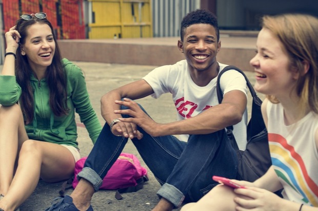 A group of young people sit around laughing and talking