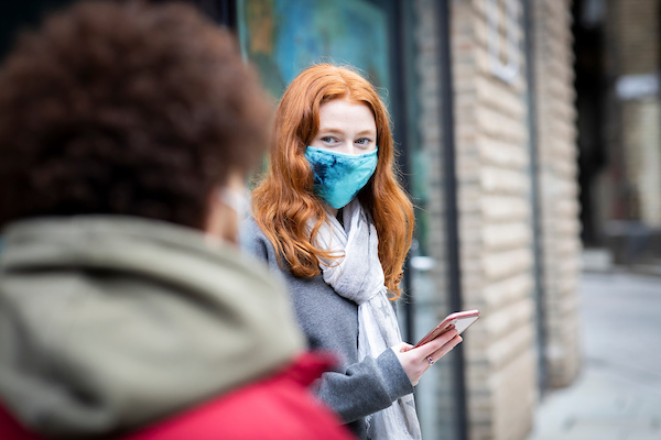 A young person is standing outside wearing a mask wondering about whether to try hypnotherapy