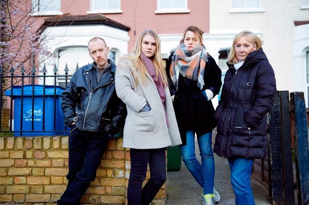 Two girls and parents stood outside a home