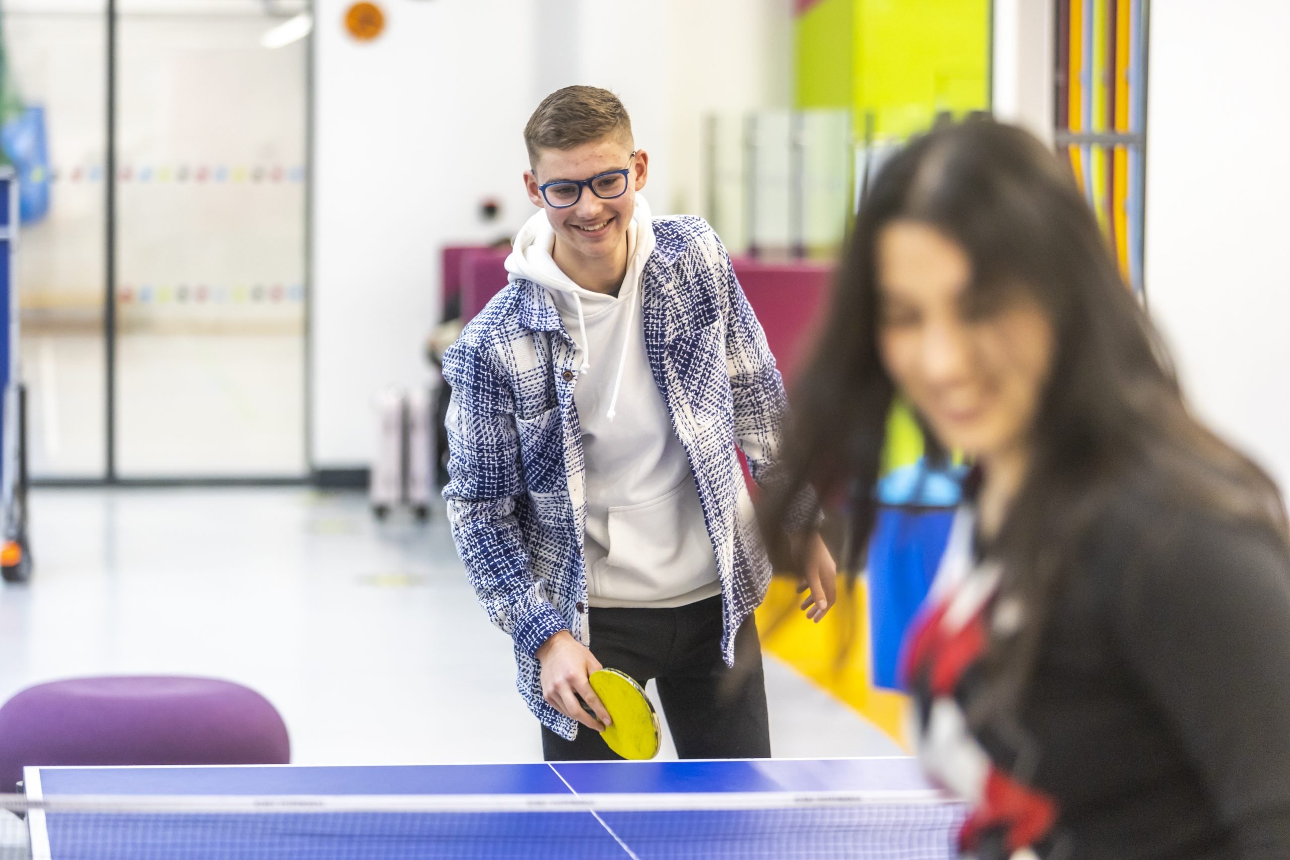 A young man is playing ping pong. He is a cross dresser.