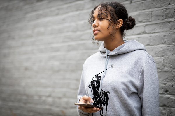 A young woman is on her phone. She feels empowered having recovered from sexual abuse and self harm. This is a wide-angle image.