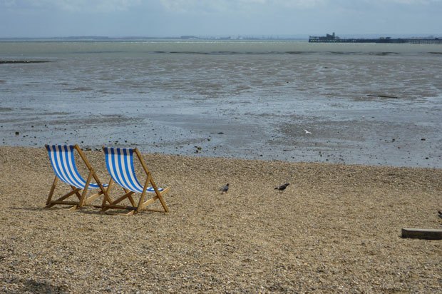Two deckchairs on beach overlooking the sea.