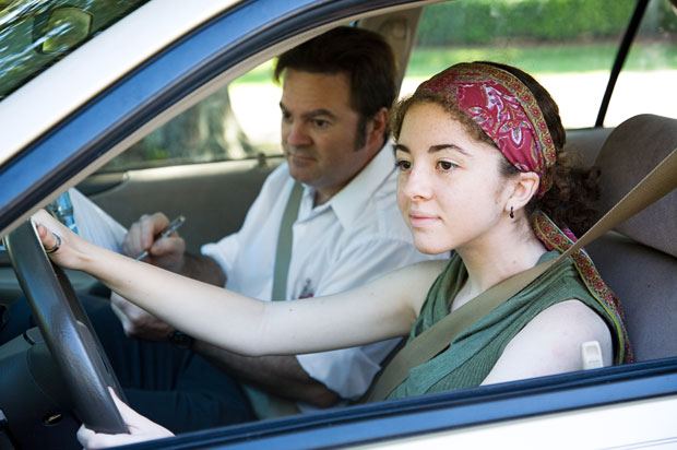 A young person is in a car with their instructor, taking a driving test