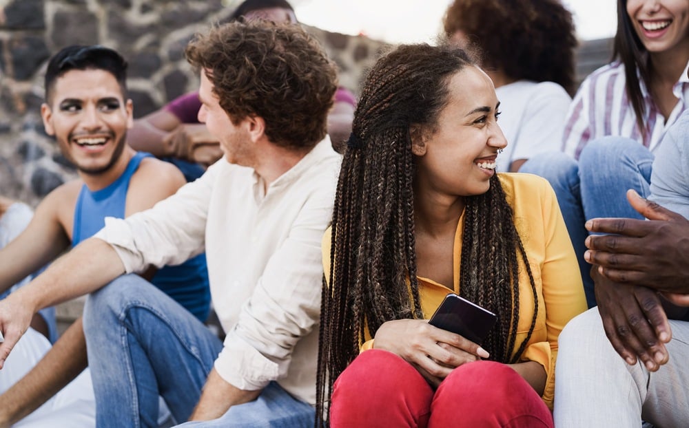 A group of friends is at a football match. One of the young women are thinking about her close friends leaving her out. This is a wide-angle image.