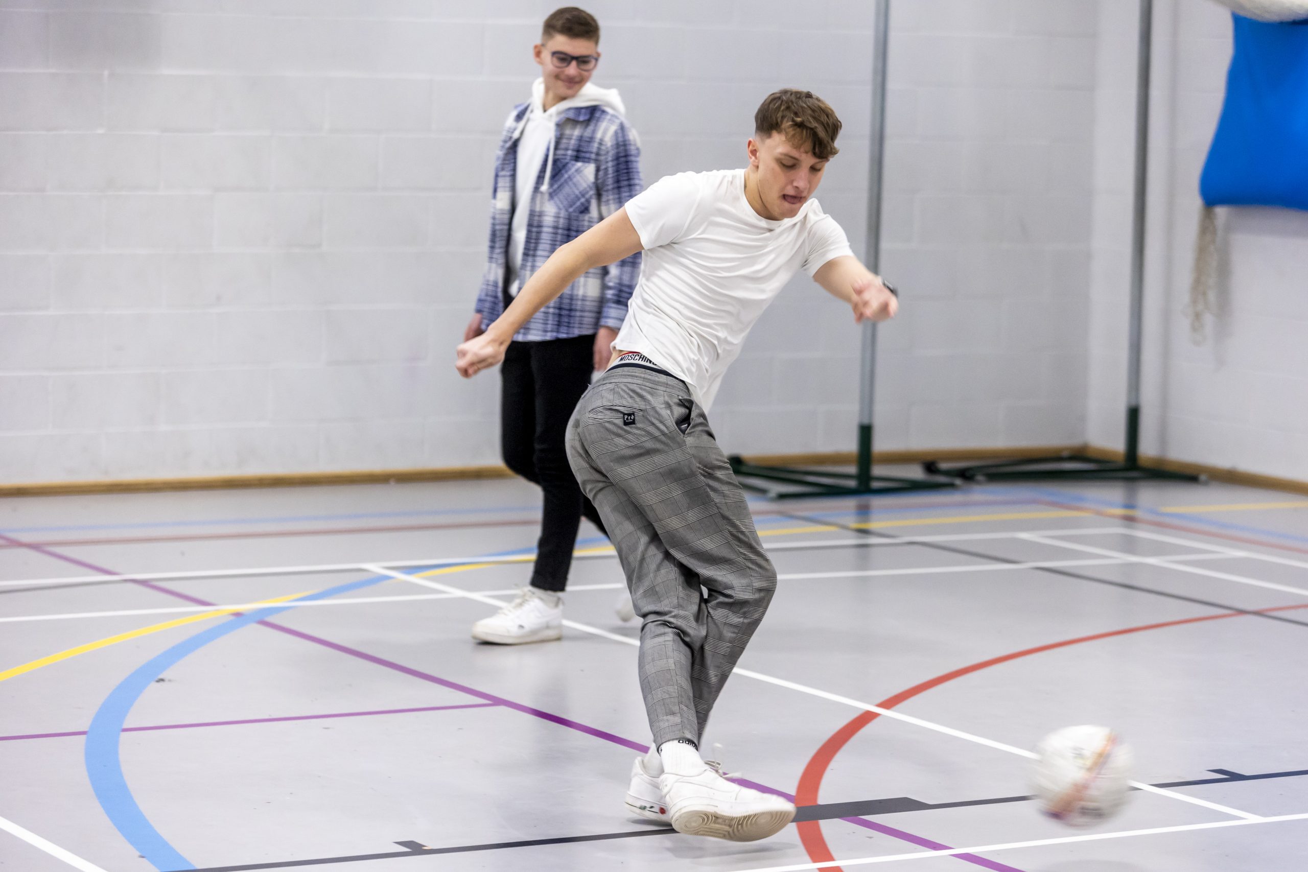 Photo shows a two young men playing football in a gym
