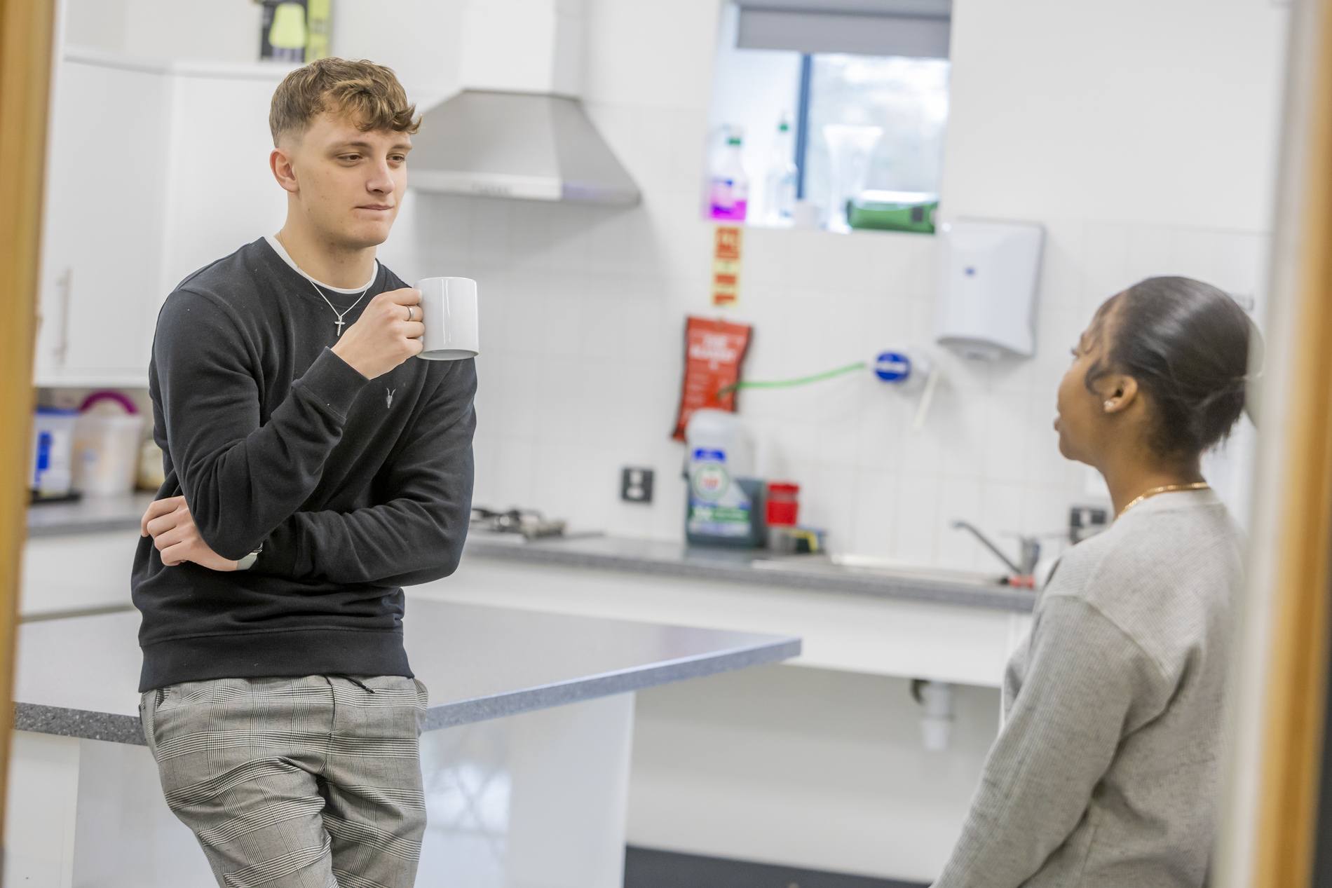 Two young people are in a kitchen. They are thinking about hot and cold relationships. This is a wide-angle image.