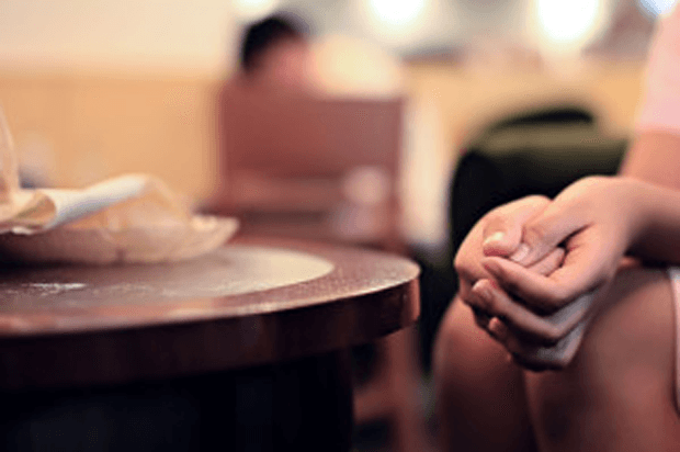 Image of the hands of a girl sitting by a table