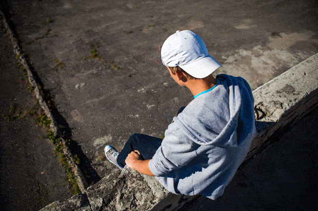 boy in cap sits on a wall