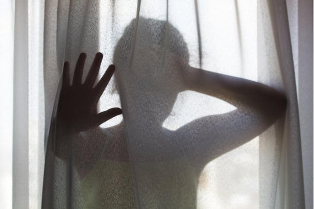 A women holds her hand up behind a curtain