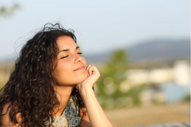 A young woman sits with her eyes closed looking peaceful
