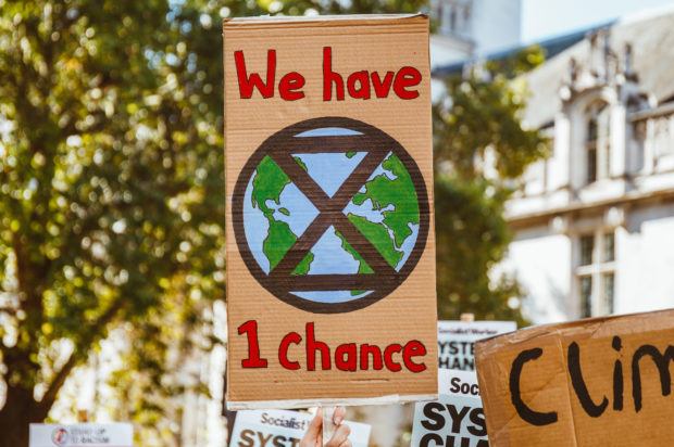 The image shows a sign at the climate strike that reads "We have 1 chance." The image is an earth with egg timer on it. 