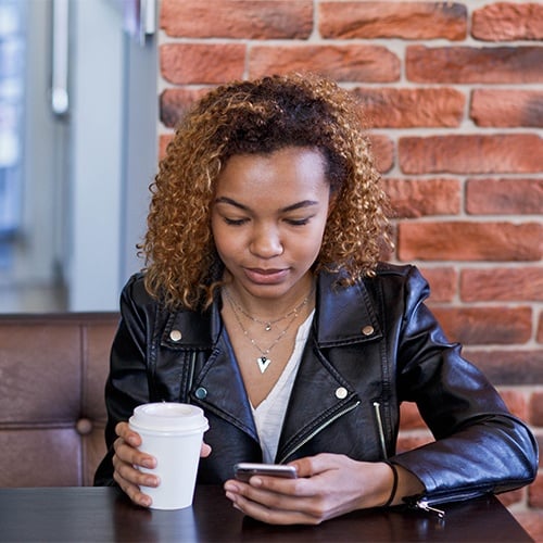 A young person sits using their phone.