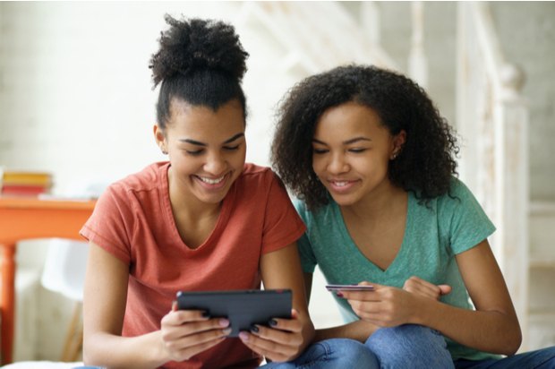 Two young people are using a tablet to buy something on a bank card