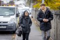 Two young people are walking down the street wearing coats and talking to each other about antidepressants