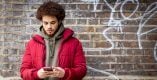 A young person is on their phone standing outside