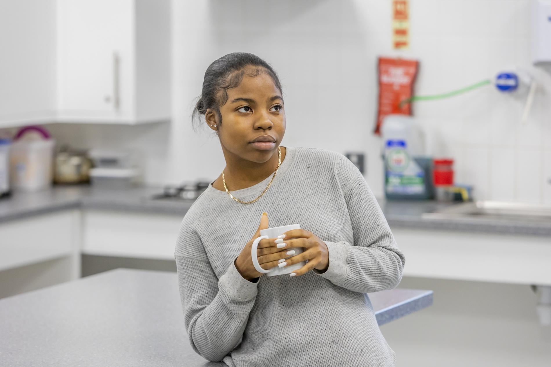 A young person is holding a cup of tea, thinking about where to find support for anorexia