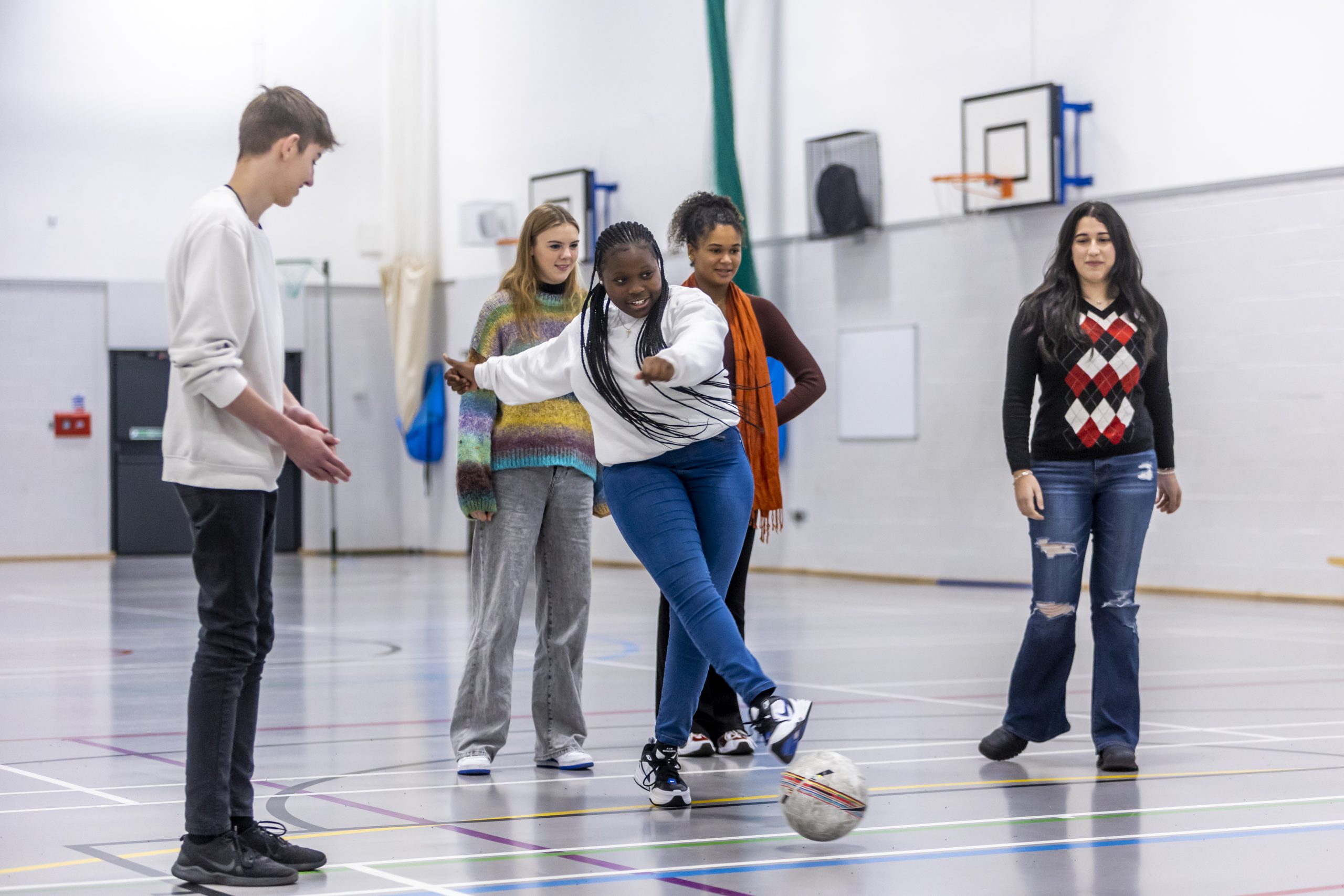 A group of young people play football in a gym