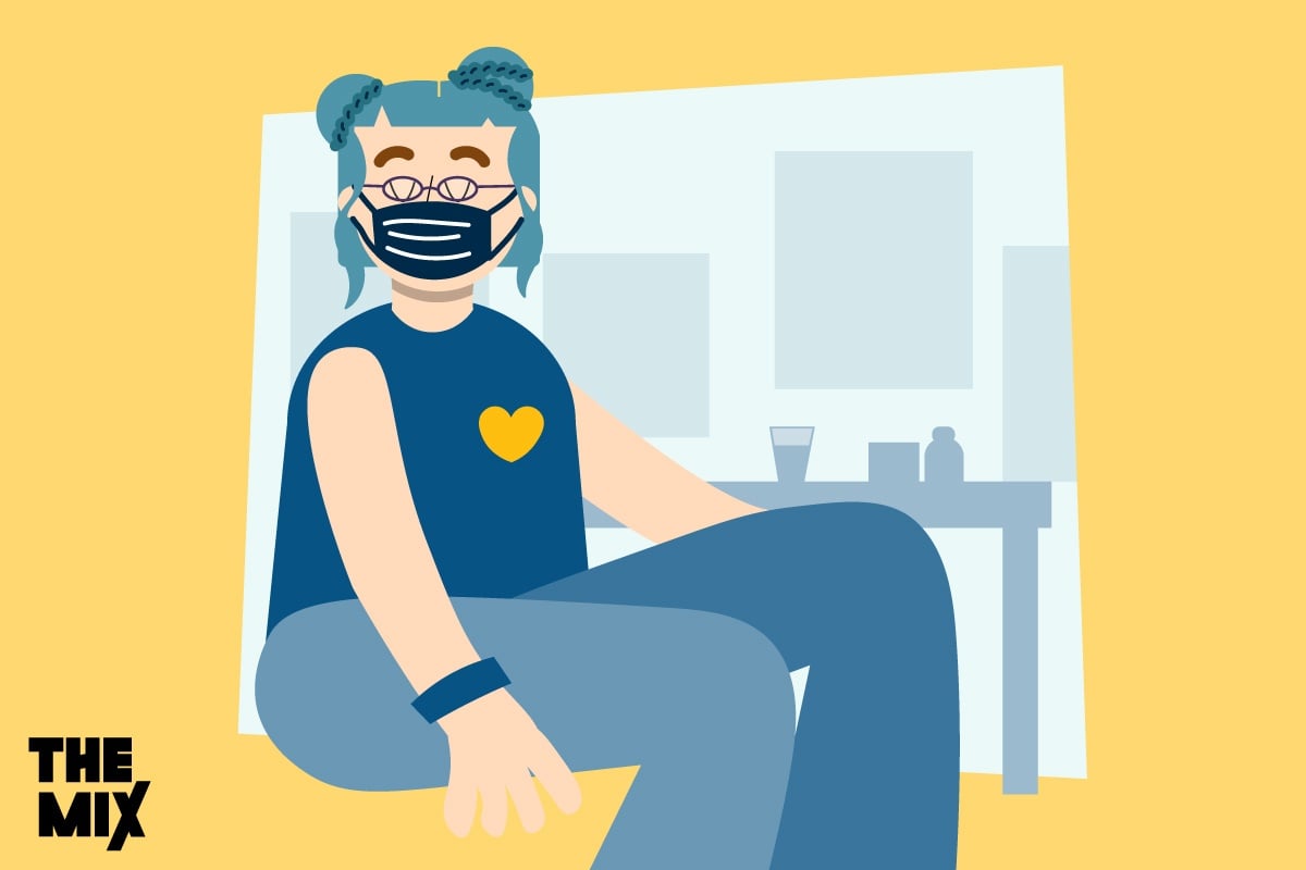 A young person is wearing a mask and a blue vest witha yellow heart on it, representing Long Covid recovery