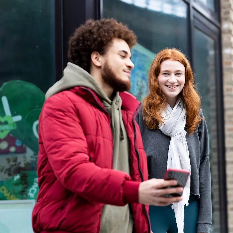 Two young people, a male and female, smile in conversation